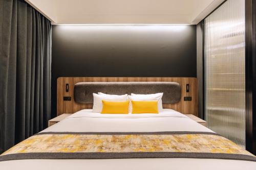 a bedroom with a large bed with two yellow pillows at Bandalo Boutique Hotel - Patong Beach Road in Patong Beach