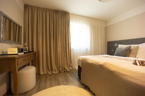 a hotel room with two beds and a desk and a window at Wellness Hotel Volarik in Mikulov