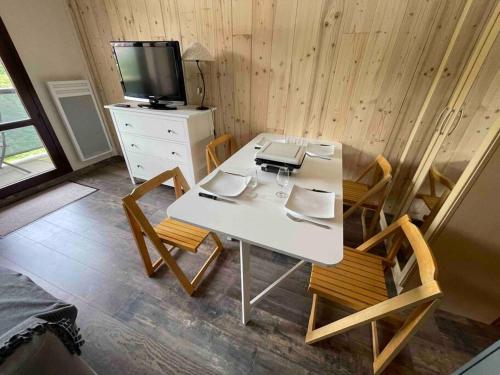 a room with a white table and chairs and a tv at Studio refait à neuf avec balcon - Famille - Parking couvert in Chamrousse