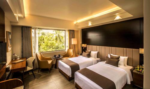 Cette chambre comprend 2 lits et une fenêtre. dans l'établissement The Monarch Hotel & Convention Centre, à Trivandrum