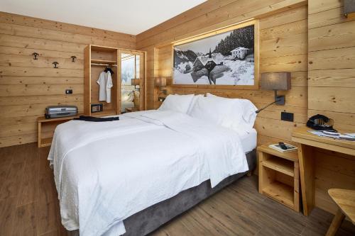 Cette chambre en bois comprend un grand lit blanc. dans l'établissement Hotel Garni dello Sportivo, à Madonna di Campiglio