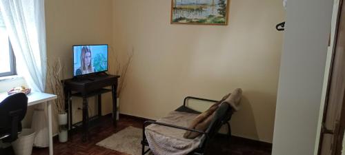 a living room with a chair and a television at Casa das Tílias in Coimbra