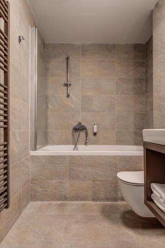 a bathroom with a tub and a toilet at Wellness Hotel Volarik in Mikulov