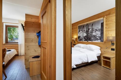 a bedroom with a white bed and a wooden wall at Hotel Garni dello Sportivo in Madonna di Campiglio