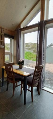 een eetkamer met een tafel en 2 stoelen en een raam bij Atlanterhavsveien Rorbuer in Averoy