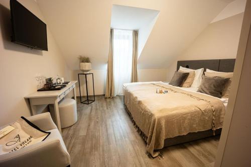 a bedroom with a bed and a desk and a television at Wellness Hotel Volarik in Mikulov