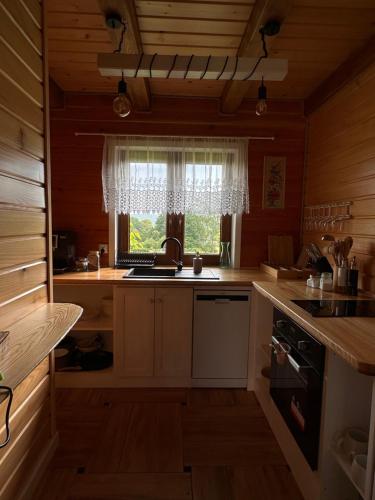 a kitchen with wooden cabinets and a window with a sink at Cabanówka in Hoczew