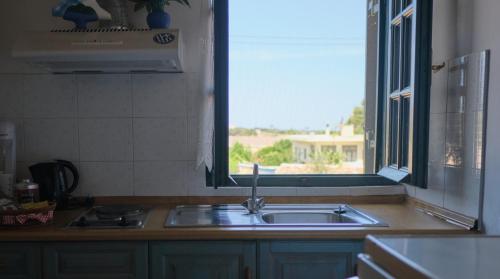 a kitchen counter with a sink and a window at Koralia Apartments in Kythira