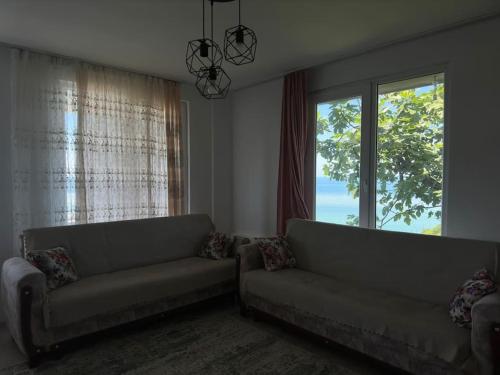 ein Wohnzimmer mit 2 Sofas und einem großen Fenster in der Unterkunft Denize Karşı Huzur Dolu Komple Kır Evi 