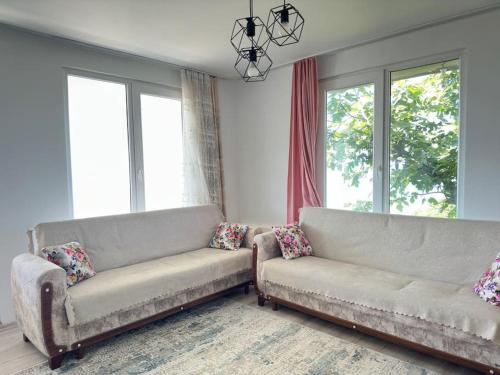 a living room with two couches and two windows at Denize Karşı Huzur Dolu Komple Kır Evi 