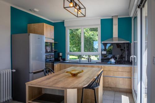 - une cuisine avec une table en bois et des murs bleus dans l'établissement La Trésorerie, à Guer