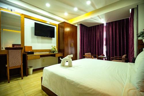 a hotel room with a bed and a desk and a television at Happy Light Central Nha Trang in Nha Trang