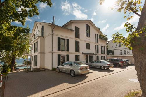 ein großes weißes Gebäude mit Autos auf einem Parkplatz in der Unterkunft Villa Friede-Marie App Freya in Sassnitz