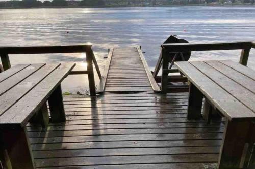 two wooden benches sitting on a dock near the water at Villa Valjensa in Sölvesborg