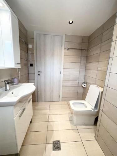 a bathroom with a white toilet and a sink at Elounda Port Apartment in Elounda