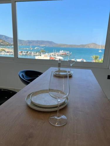 a wooden table with two wine glasses on it at Elounda Port Apartment in Elounda