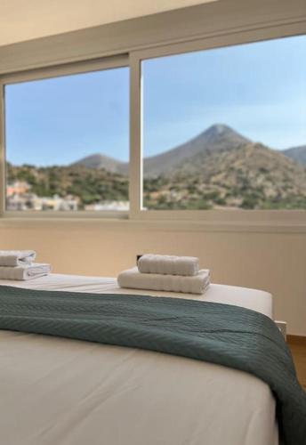 a bed with two towels on top of it in front of a window at Elounda Port Apartment in Elounda