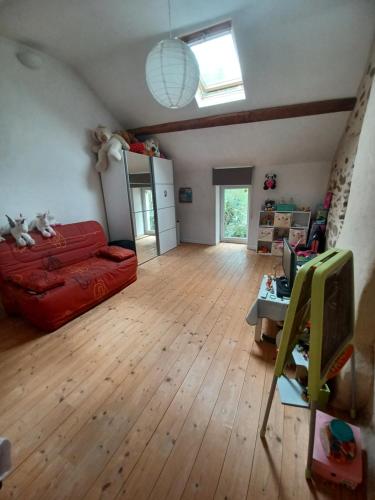 a living room with a red couch and wooden floors at Maison avec piscine et spa gonflable, 2 chats présents in Saint-Étienne-de-Montluc