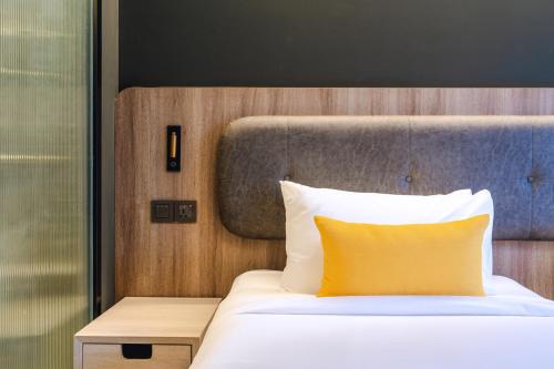 a bedroom with a bed with a yellow pillow at Bandalo Boutique Hotel - Patong Beach Road in Patong Beach
