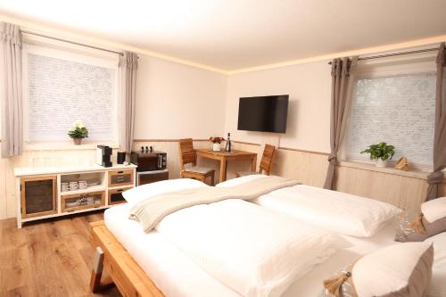 a bedroom with a large white bed and a television at AlbLodges in Bitz