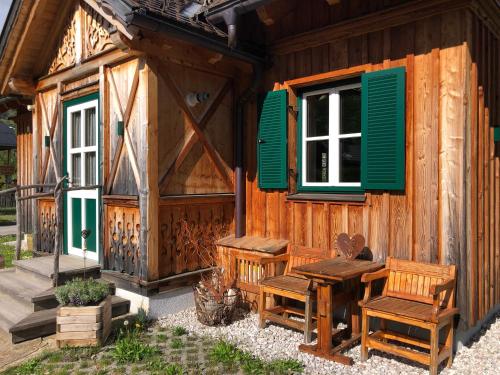 a wooden cabin with green windows and a table and chairs at Chalet Altaussee in Altaussee
