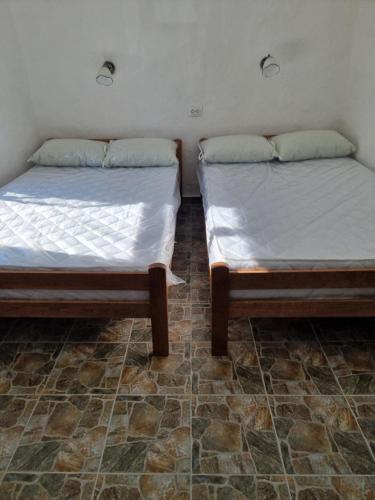 two beds sitting next to each other in a room at Apartmani kod Kmeta in Janja