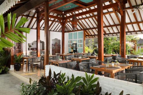 un restaurante al aire libre con mesas y sillas de madera en Puri Tempo Doeloe Boutique Hotel, en Sanur