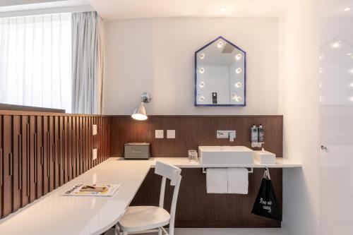 a bathroom with a sink and a mirror at Ruby Zoe Hotel London in London