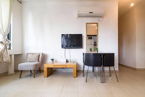 ein Wohnzimmer mit einem Tisch, Stühlen und einem TV in der Unterkunft 2 rooms close to beach in Tel Aviv