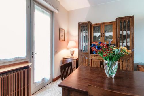 a vase of flowers on a wooden table in a room at Mulino Nuovo by Quokka 360 - spacious apartment on the Swiss border in Como