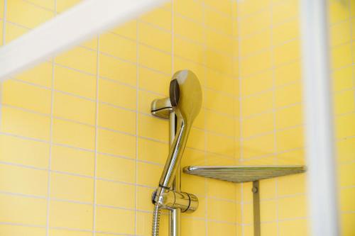 a shower with a shower head on a yellow tiled wall at Mulino Nuovo by Quokka 360 - spacious apartment on the Swiss border in Como