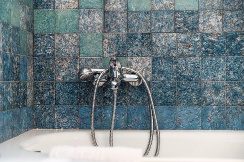 a bath tub with a shower in a blue tiled bathroom at Mulino Nuovo by Quokka 360 - spacious apartment on the Swiss border in Como