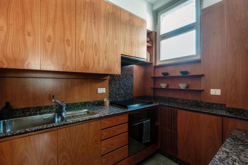 a kitchen with wooden cabinets and a sink and a window at Mulino Nuovo by Quokka 360 - spacious apartment on the Swiss border in Como