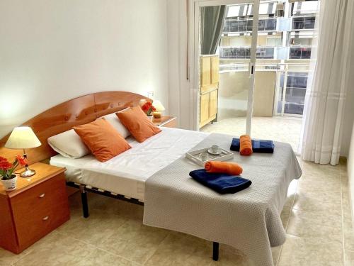 a bedroom with a bed and a table with towels on it at APARTBEACH NOVA PINEDA 3º y VISTAS PISCINA in La Pineda
