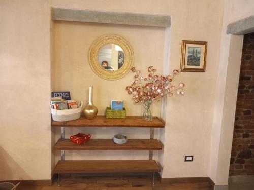 - une étagère dans une pièce avec un miroir et des fleurs dans l'établissement Casa Clery, stile toscano, vicino a firenze, à Montelupo Fiorentino