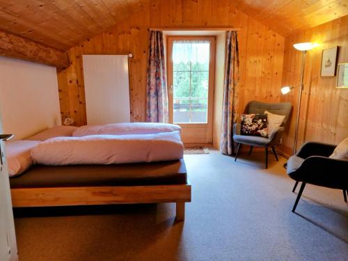 a bedroom with two beds and a chair and a window at 2 Zimmer Ferienwohnung Davos-Glaris in Glaris