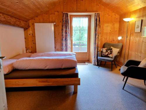a bedroom with two beds and a chair and a window at 2 Zimmer Ferienwohnung Davos-Glaris in Glaris