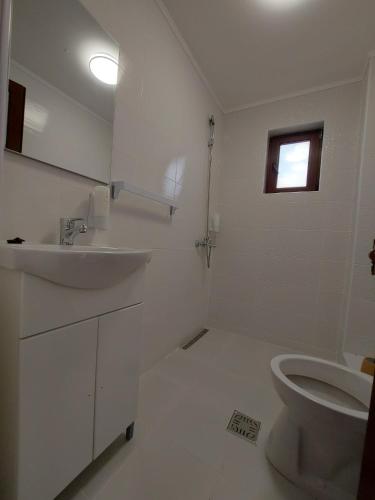 a white bathroom with a sink and a toilet at VILA OPAL in Tuzla