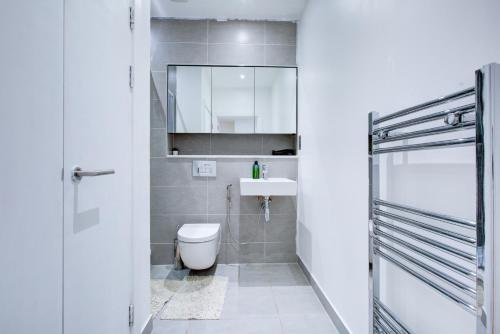 a bathroom with a toilet and a sink and a mirror at Statera Apartments - City Terraces in London