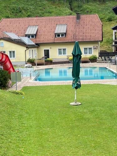 a green umbrella sitting in the grass near a swimming pool at Ferienwohnung im Nationalpark Gesäuse in Hieflau
