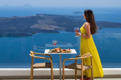 een vrouw in een gele jurk met een glas wijn bij Ira Hotel & Spa - Adults Only in Firostefani