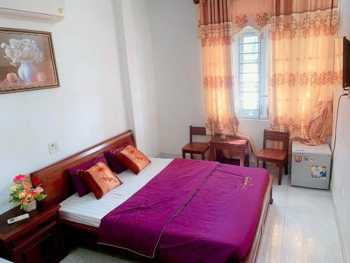 Un dormitorio con una cama con sábanas moradas y una ventana en Gia Hoang Hotel, en Quy Nhon