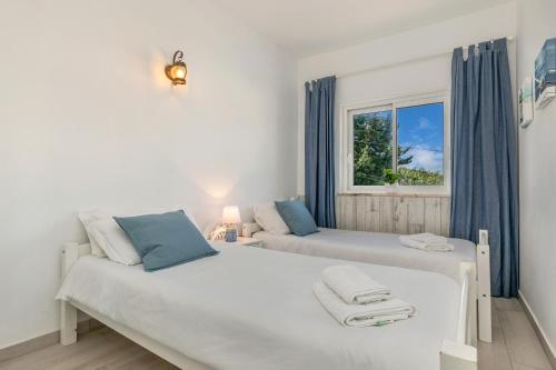 two beds in a room with a window at Bela Vista Burgau in Burgau