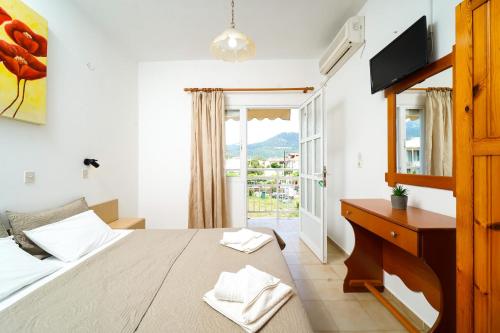 a bedroom with a bed and a desk and a window at Studios Pinelopi in Skala Potamias