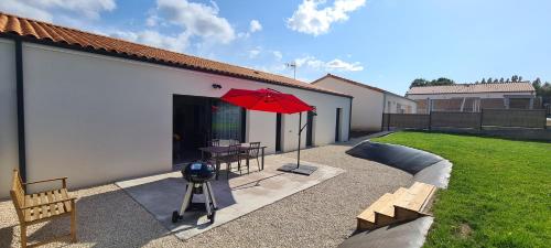 a patio with a table and a red umbrella at Gîte la Couzinette 3km du parc Puy du Fou in Les Épesses