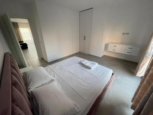 een witte kamer met een bed en een dressoir bij Appartamenti Nicola in Durrës