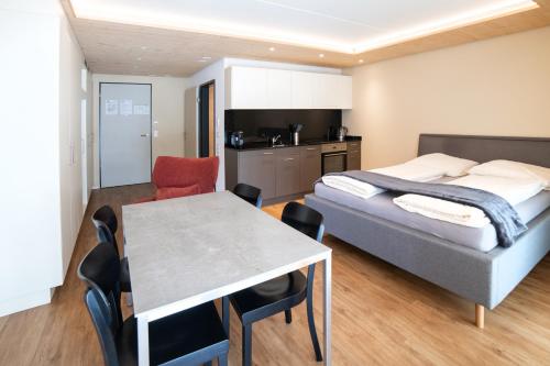 a bedroom with a bed and a table and a kitchen at WAZ Wohnen auf Zeit - Flums in Flums