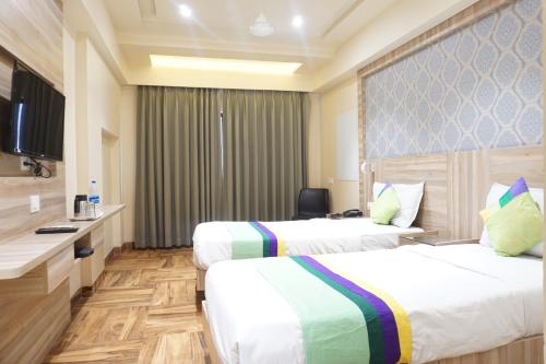 a hotel room with two beds and a television at Treebo Classic Grande, Camp in Pune