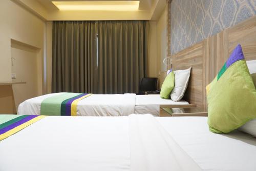 a hotel room with two beds with green pillows at Treebo Classic Grande, Camp in Pune