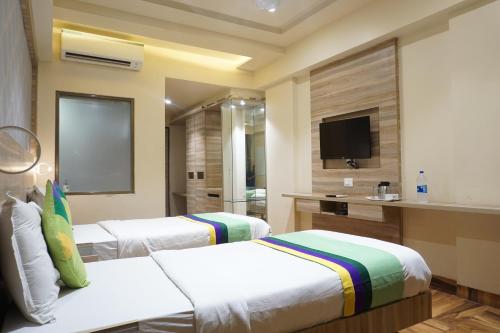 a hotel room with two beds and a flat screen tv at Treebo Classic Grande, Camp in Pune